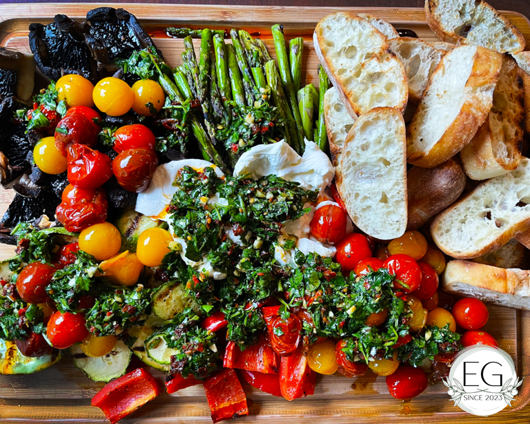 Charcuterie board overflowing with vegetables, cheeses and breads.