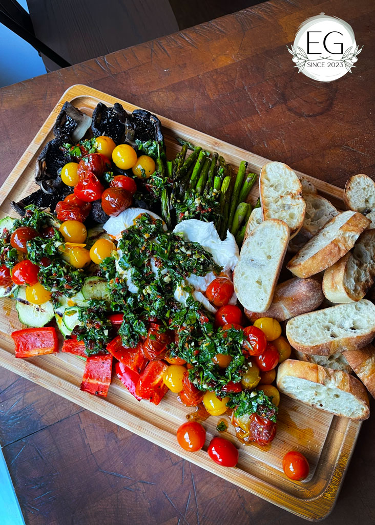 Charcuterie board overflowing with mixed vegetables, sauces, and cheeses.